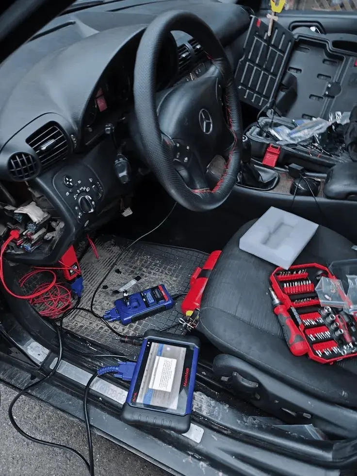 Автоэлектрик подключает диагностический сканер к разъёму OBD-II